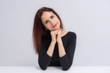 Güzel esmer kız masada beyaz bir arka plan üzerinde konuşurken kavramı. O farklı pozlar farklı duygular ile kamera önünde oturur.