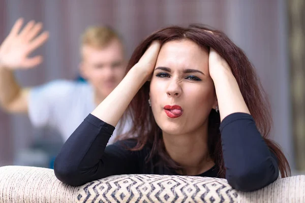 The concept of family conflict, family problems, family relationships of young disgruntled husband and wife in a room on the sofa. They sit across from each other and look displeased.