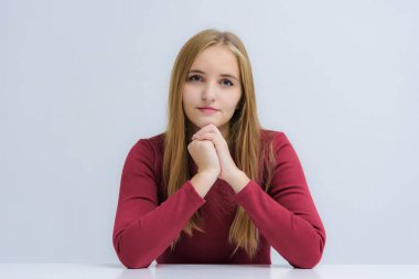 Kavram gülümseyerek, masada otururken duyguları ile konuşurken beyaz bir arka plan üzerinde güzel bir mutlu sarışın kız portresi. Doğrudan çeşitli teşkil etmektedir kamera önünde duruyor.