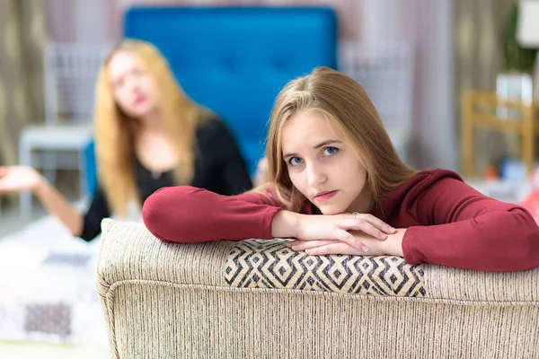 The concept of family problems a couple of beautiful young disgruntled lesbian girls are talking in a room sitting on a sofa. They are right in front of the camera and look unhappy.