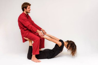 Fotoğraf Yoga katta iki germe ve beyaz bir arka plan üzerinde rahatlatıcı için poz veriyor. Adam kadın kamera önünde uzanır.