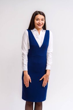 Stüdyo bir elbise beyaz bir arka plan üzerinde güzel bir esmer kız portresi. Gülümseyen ve mutlu görünüyordu şu kamera önünde duruyor.