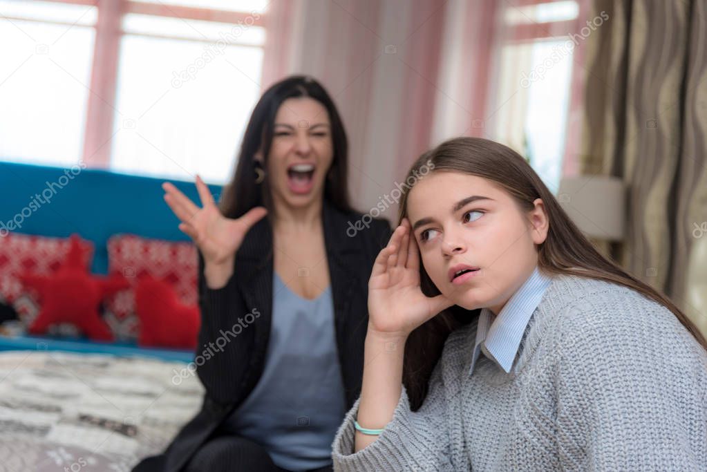 Family problems, family relationships mother and teen daughter in a room on the sofa. They sit on the sofa and look displeased.