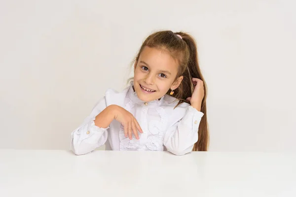 テーブルに白い背景の上のかわいい女の子の肖像画 笑顔と幸せそうに見えて 子供は カメラの前に右 — ストック写真