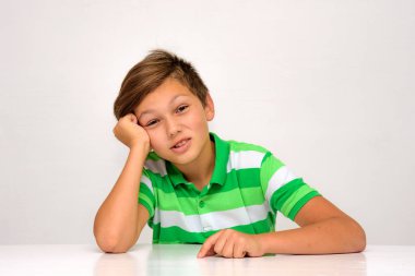 Stüdyo portre farklı duygular bir masada oturan bir beyaz zemin üzerine bir genç çocuk. Farklı pozlar kamera önünde oturuyor.