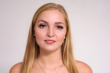 Güzel sarışın kız beyaz zemin üzerinde bir close-up stüdyo portre. O kamera önünde duruyor ve farklı duygular gösterir