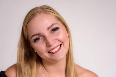 Güzel sarışın kız beyaz zemin üzerinde bir close-up stüdyo portre. O kamera önünde duruyor ve farklı duygular gösterir