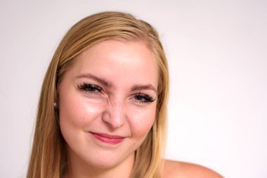 Güzel sarışın kız beyaz zemin üzerinde bir close-up stüdyo portre. O kamera önünde duruyor ve farklı duygular gösterir