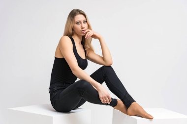 Beyaz bir arka plan üzerinde gülümseyen güzel sarışın kız portresi konsept ürünü tanıtır. O kamera önünde haklı ve farklı duygular gösterir.