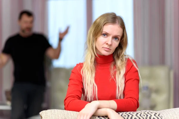 The concept of family problems, difficulties, relationships, talks disgruntled husband and wife in a room on the sofa. They are directly in front of the camera in different poses.