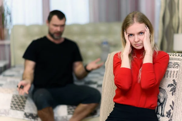 The concept of family problems, difficulties, relationships, talks disgruntled husband and wife in a room on the sofa. They are directly in front of the camera in different poses.