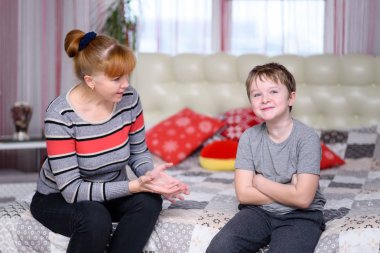 Anne ve çocuk oturup oda Windows yakınındaki, onlar yatağa otur, mücadele vardır. kızgın bir çocuktur, annesi ona bağırıyor.