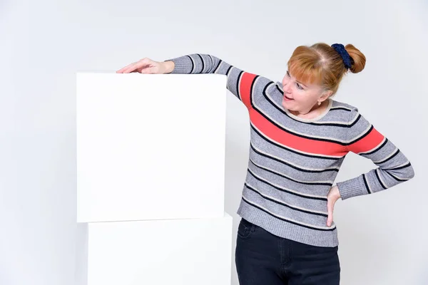 concept of a woman on a white background. He stands near the white cubes in the middle of the photo and looks at the camera or the cube, smiling.