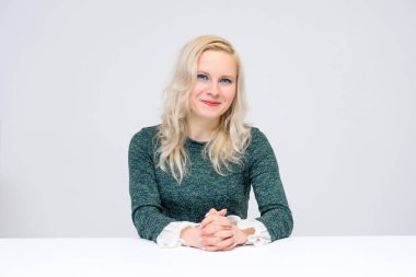 oturan kadın kavramı bir beyaz masa üzerinde beyaz bir arka plan ve onlar are ortasında belgili tanımlık çerçevelemek ve Yeşil elbiseli bir kız gülümseyerek kameraya baktığımızda, ve beyaz saçlı o makyaj vardır.