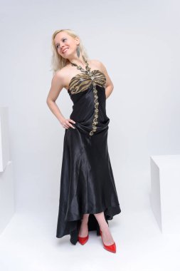 Tam büyüme beyaz bir arka plan üzerinde siyah elbiseli güzel kız sarışın kavramı studio fotoğraf portre. Gülümseyen ve mutlu görünüyordu çeşitli pozlar kamera önünde duruyor.