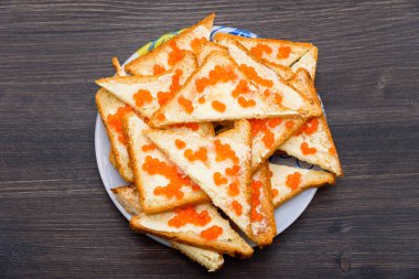 Tereyağı ve kırmızı havyar, yeşil salata yaprağı, ahşap rustik masa sandviçle. Kırmızı havyar ile sandviç. somon karaca. Deniz ürünleri. Lezzetli lezzetli Aperatif