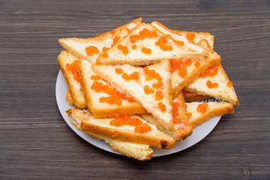 Tereyağı ve kırmızı havyar, yeşil salata yaprağı, ahşap rustik masa sandviçle. Kırmızı havyar ile sandviç. somon karaca. Deniz ürünleri. Lezzetli lezzetli Aperatif