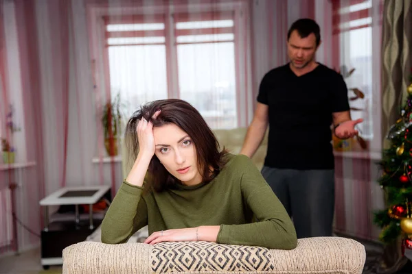 The concept of the wife with the husband sitting in the room against the window and argue. they are in the middle of the photo and talk about something.