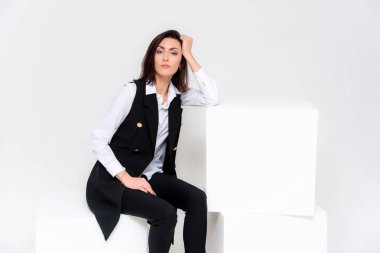 Kavramı farklı pozlar farklı duygular ile iş takım elbiseli, beyaz bir arka plan üzerinde oturan bir kız portresi. Bu çerçeve, beyaz küpleri yanında ortasında sonraki başka bir küp olduğunu.