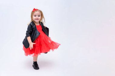 Şirin güzel bir kız bebek beyaz bir arka planda bir moda kırmızı elbiseli kavramı portresi. O doğrudan farklı pozlar kamera önünde duruyor ve farklı duygular gösterir.