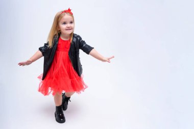 Şirin güzel bir kız bebek beyaz bir arka planda bir moda kırmızı elbiseli kavramı portresi. O doğrudan farklı pozlar kamera önünde duruyor ve farklı duygular gösterir.