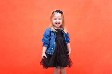 Kavram dans, konuşurken, moda giysiler içinde kırmızı bir arka plan üzerinde gülümseyen sevimli güzel kız çocuk portresi. O farklı duyguları ile farklı pozlar kamera önünde oturur.