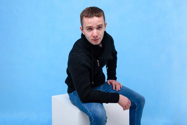 Концептуальный Студийный Портрет Молодого Человека Синем Фоне Сидящего Кубе Сидит — стоковое фото