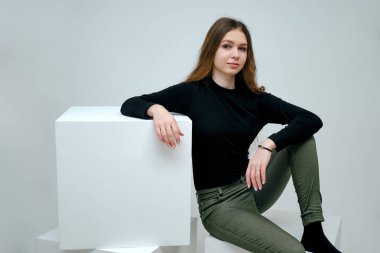 Kavram portre siyah t-shirt beyaz bir arka plan üzerinde gülümseyen içinde bir güzel dost ve iyimser mutlu genç kız esmer. Güzel iş kadını beyaz küp üzerinde kopya alanı gösterilen.