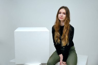 Kavram portre siyah t-shirt beyaz bir arka plan üzerinde gülümseyen içinde bir güzel dost ve iyimser mutlu genç kız esmer. Güzel iş kadını beyaz küp üzerinde kopya alanı gösterilen.