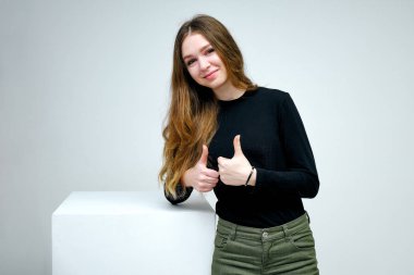 Kavram portre siyah t-shirt beyaz bir arka plan üzerinde gülümseyen içinde bir güzel dost ve iyimser mutlu genç kız esmer. Güzel iş kadını beyaz küp üzerinde kopya alanı gösterilen.