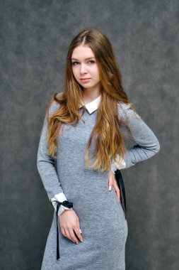 Mutlu brunet kız güzel uzun saçlı hoş bir dostu Müdürü kavramı portresi. Tam büyüme gri bir arka plan karşı gülümseyen bir gri elbiseli duruyor.