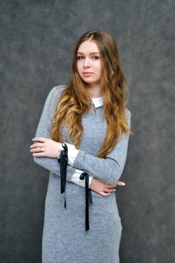 Mutlu brunet kız güzel uzun saçlı hoş bir dostu Müdürü kavramı portresi. Tam büyüme gri bir arka plan karşı gülümseyen bir gri elbiseli duruyor.