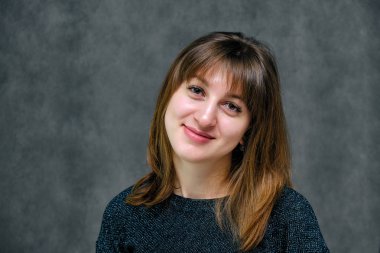 Kavram portre güzel genç esmer kadın yüzü gri studio kapatın. Mutlu gülen genç kız doğal makyaj ve güzel bir gülümseme ile. Gri bir arka plan üzerinde kadın portre