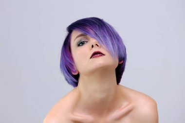 Mor saç ve kısa saç kesimi güzel, seksi bir kızla fotoğraf ortasında beyaz bir arka plan ve palyaçoluk oturur. Çıplak ve görünür omuz bir kız.