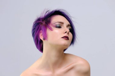 Mor saç ve kısa saç kesimi güzel, seksi bir kızla fotoğraf ortasında beyaz bir arka plan ve palyaçoluk oturur. Çıplak ve görünür omuz bir kız.