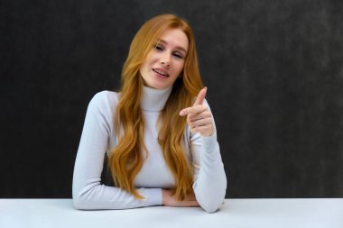 Kavramı Studio masada oturan gri bir arka plan üzerinde konuşmak güzel güzel kızıl saçlı kız portresi. O beyaz bir kazak giyiyor ve farklı duygular içinde farklı pozlar gösterir.