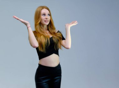 Kavram portre sevimli güzel kızıl saçlı kızın gri bir arka plan stüdyo ayakta kamera önünde konuşurken. Farklı pozlar farklı duygular gösterir.