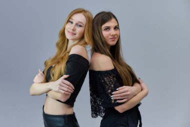 İki sevimli güzel kız stüdyoda gri bir arka plan üzerinde konuşurken kavramı portresi kamera önünde bekliyoruz. Farklı pozlar farklı duygular gösteriyorlar.