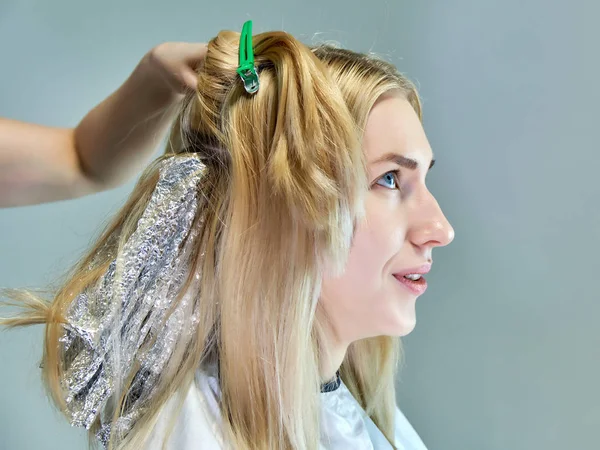 Trabalho de conceito de um esteticista cosmetologista com escritório. Faz cabelo, aplica maquiagem em um fundo cinza . — Fotografia de Stock