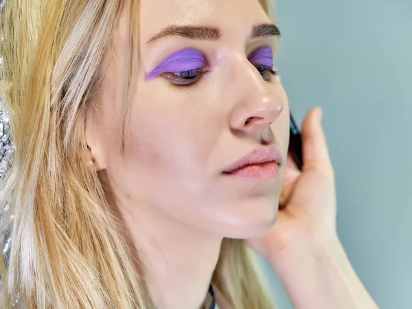 Trabajo conceptual de un cosmetólogo esteticista con oficina. Hace el pelo, aplica maquillaje sobre un fondo gris . — Foto de Stock