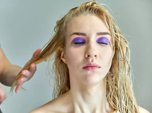Концептуальна робота косметолога в офісі. Робить волосся, наносить макіяж на сірий фон . — стокове фото