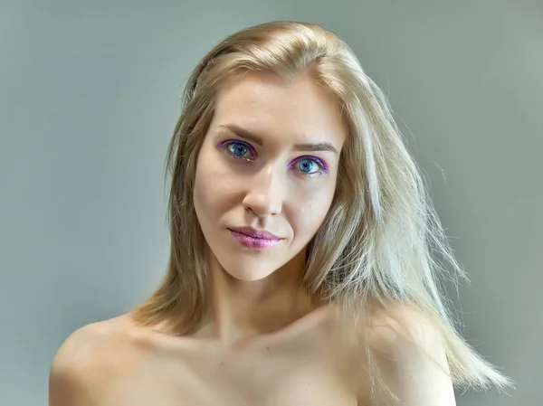 Concepto de retrato de cerca de una hermosa chica rubia sobre un fondo gris. El cabello se desarrolla en diferentes direcciones . — Foto de Stock