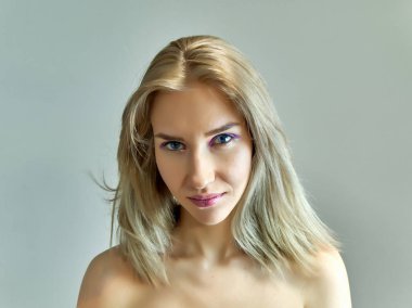 Gri bir arka plan üzerinde güzel bir sarışın kız portre kavramı. Saç farklı yönlere geliştirir.