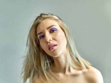 Gri bir arka plan üzerinde güzel bir sarışın kız portre kavramı. Saç farklı yönlere geliştirir.