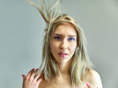 Gri bir arka plan üzerinde güzel bir sarışın kız portre kavramı. Saç farklı yönlere geliştirir.