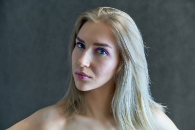 Gri bir arka plan üzerinde güzel bir sarışın kız portre kavramı. Saç farklı yönlere geliştirir.