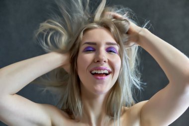 Gri bir arka plan üzerinde güzel bir sarışın kız portre kavramı. Saç farklı yönlere geliştirir.