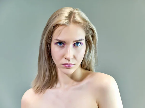 Concepto de retrato de cerca de una hermosa chica rubia sobre un fondo gris. El cabello se desarrolla en diferentes direcciones . — Foto de Stock