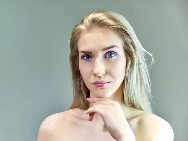 Closeup portrait concept of a beautiful blonde girl on a gray background. Hair develops in different directions. — Stock Photo, Image