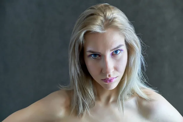 Conceito de retrato close-up de uma linda garota loira em um fundo cinza. O cabelo se desenvolve em diferentes direções . — Fotografia de Stock